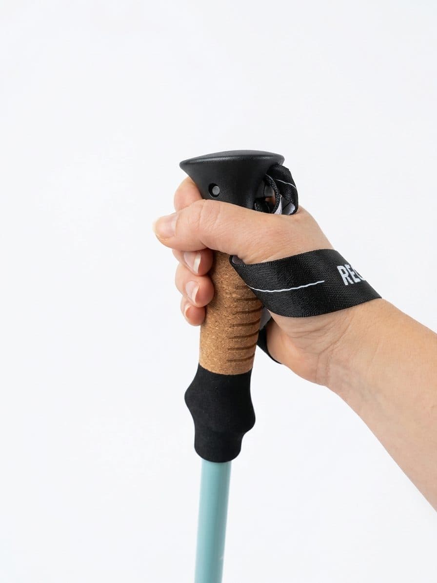 Hand holding a Recovery Walking Pole cork handle with the wrist strap in place