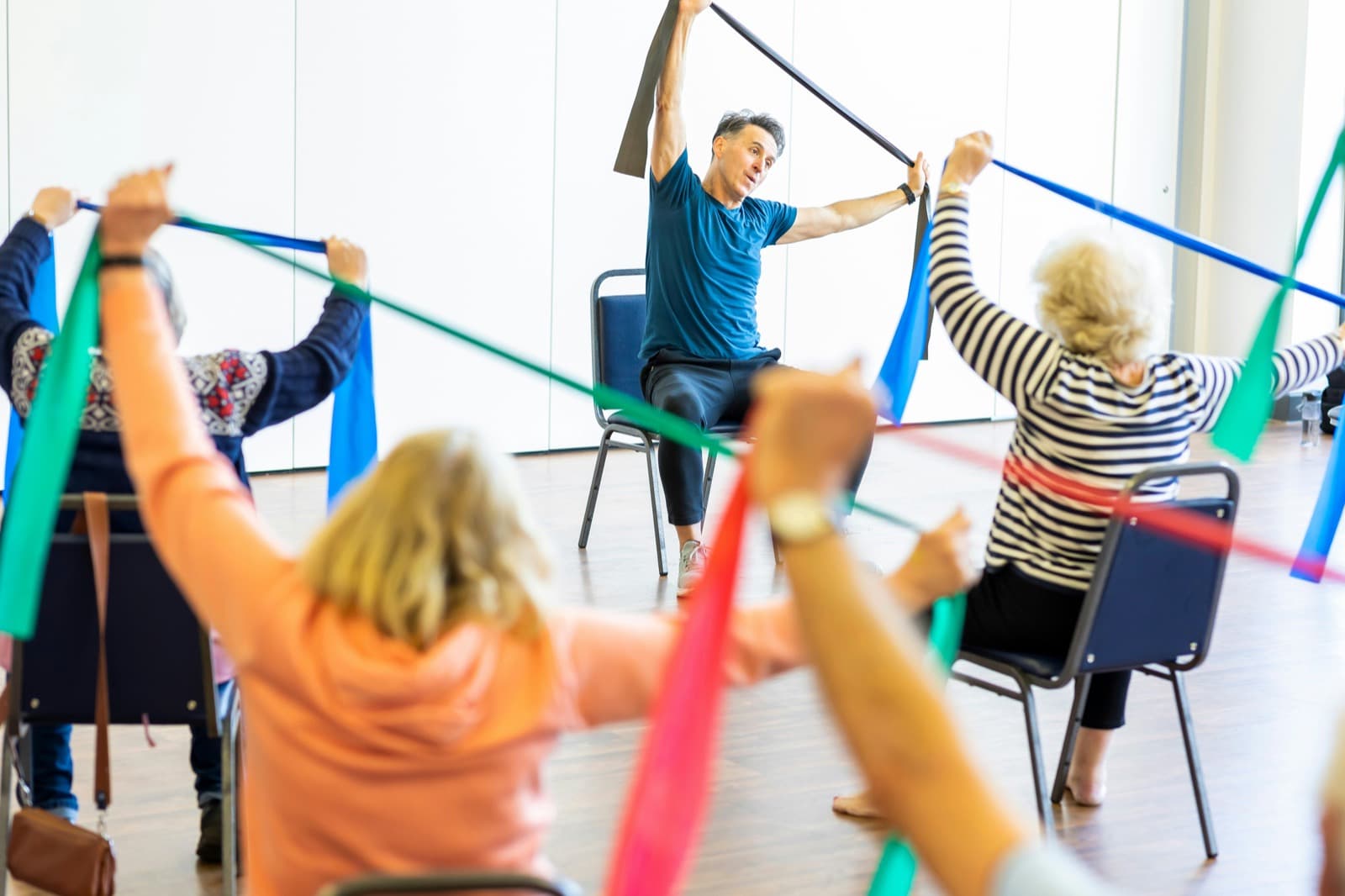 An instructor leading a seated resistance-band exercise class for older adults